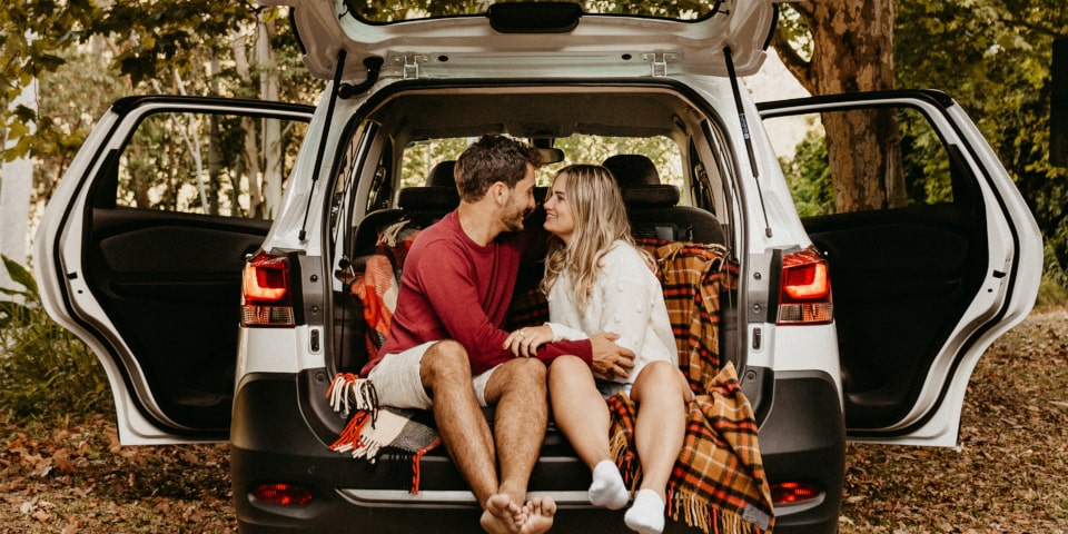 couple faisant un pique-nique dans le coffre de la voiture au milieux d'un bois